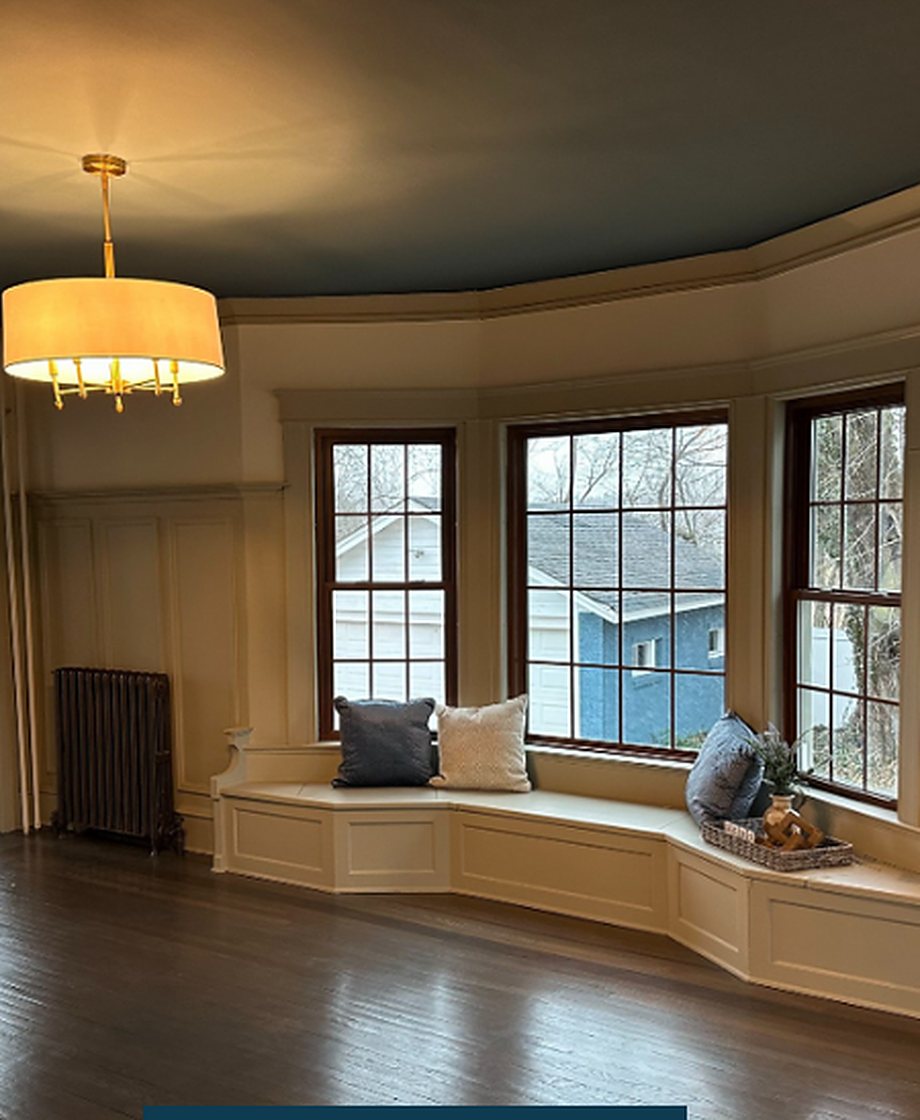 The room after: paneled window seat, brass chandelier, refinished floors