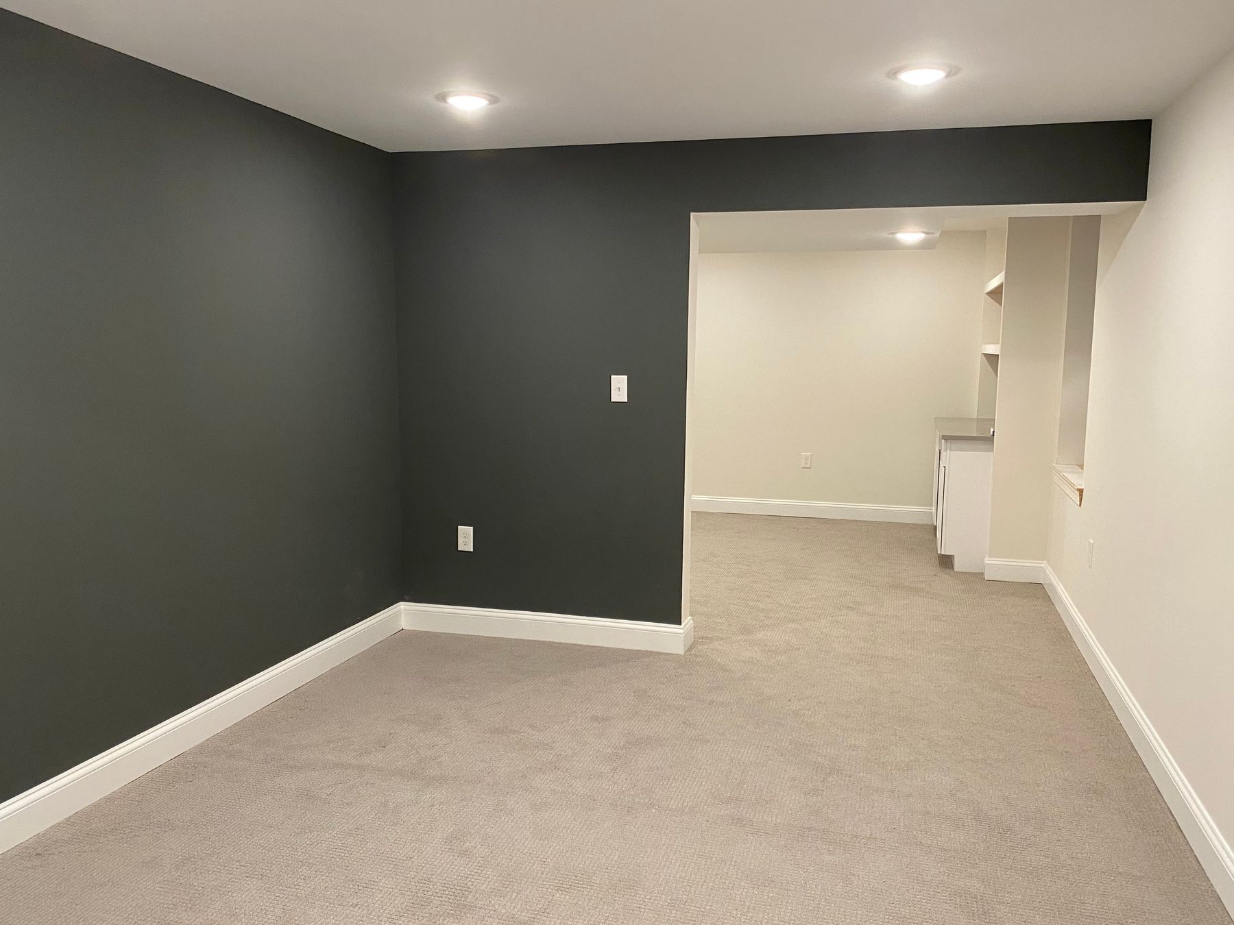 A finished basement room with a green accent wall