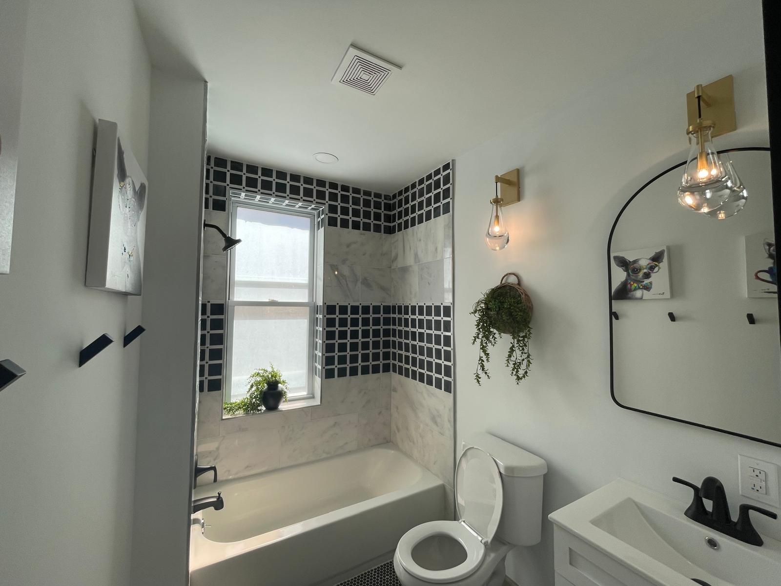 A bath with blue tile and a black-framed shower