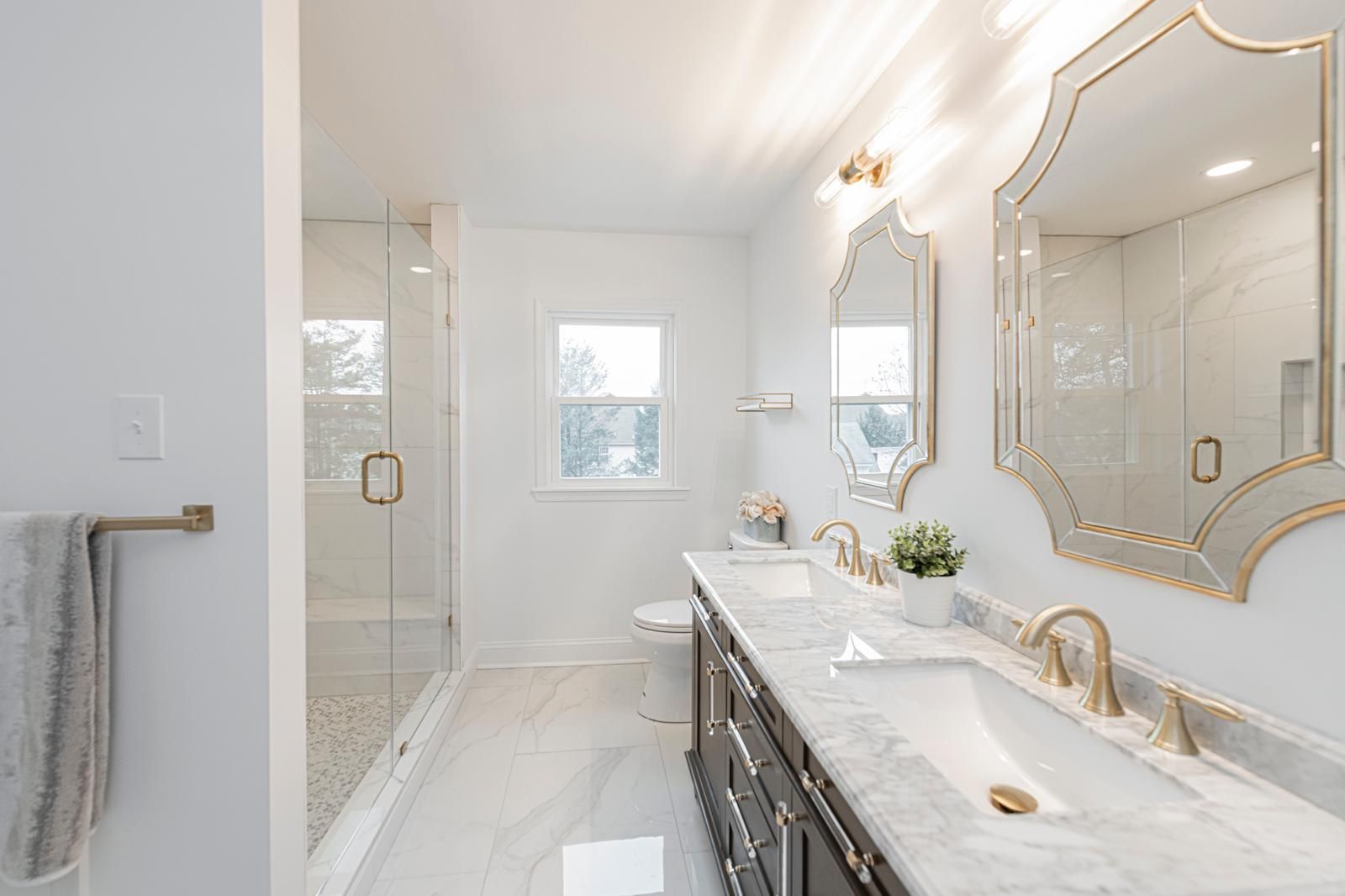 A double vanity with brass fixtures and arched mirrors