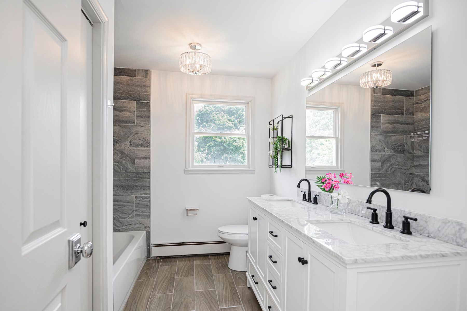 A white double vanity with a marble top and black fixtures