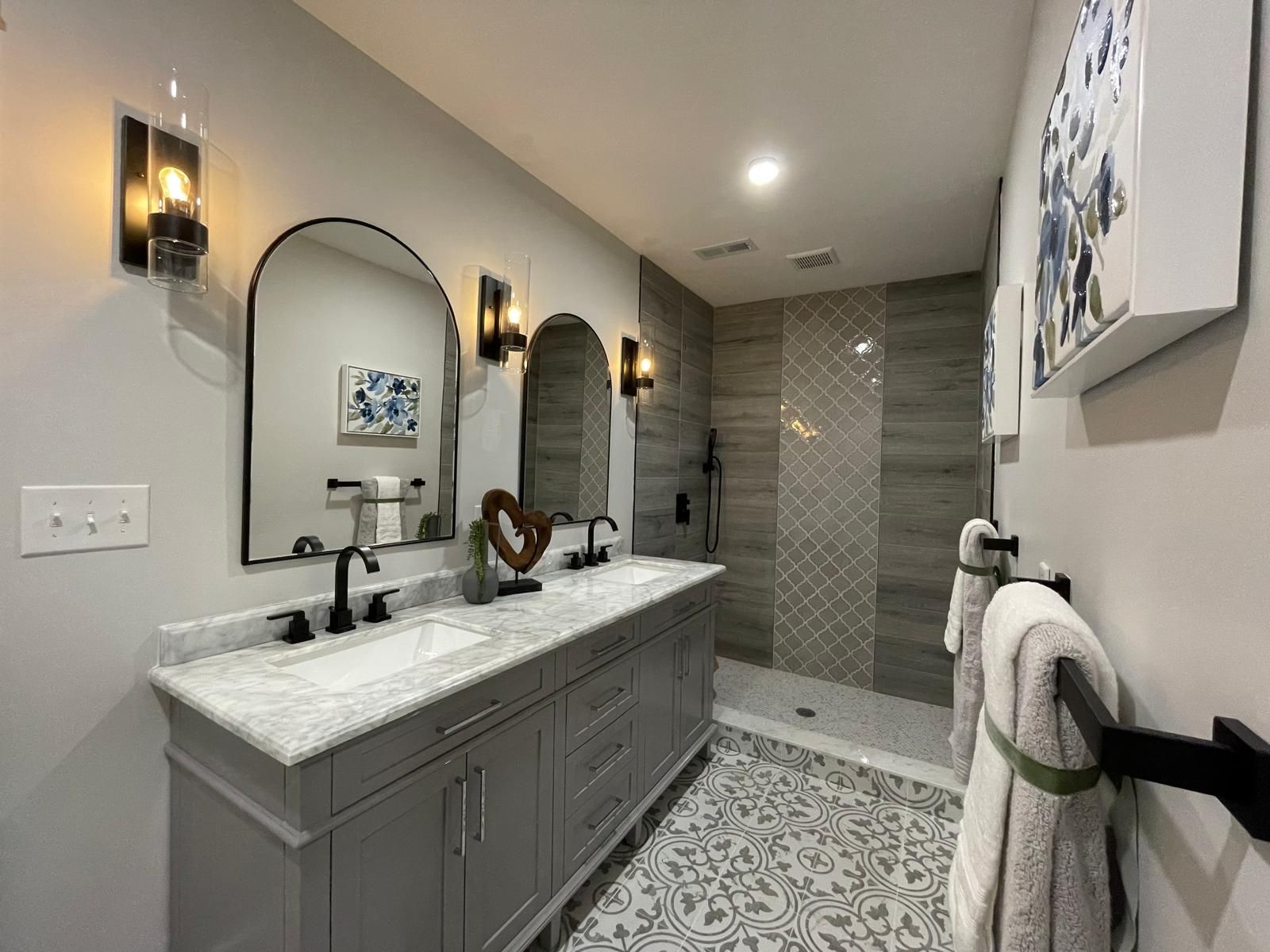 A gray vanity with a marble top and a tiled shower