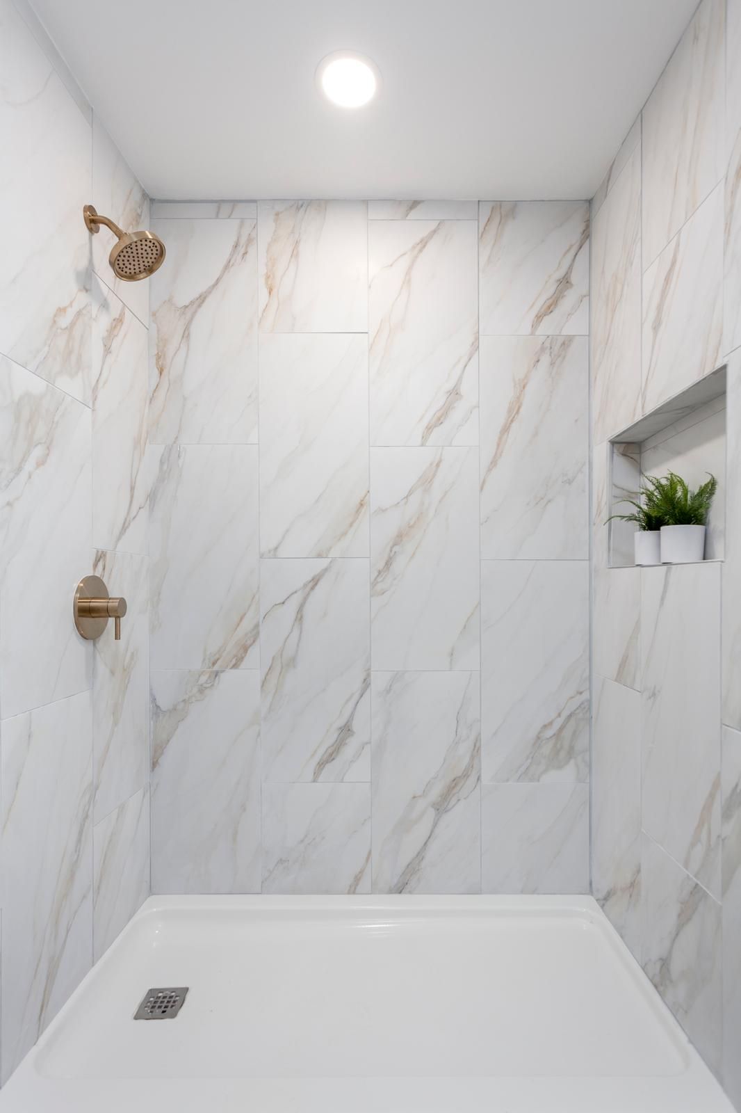 A marble-tiled shower with a rain head