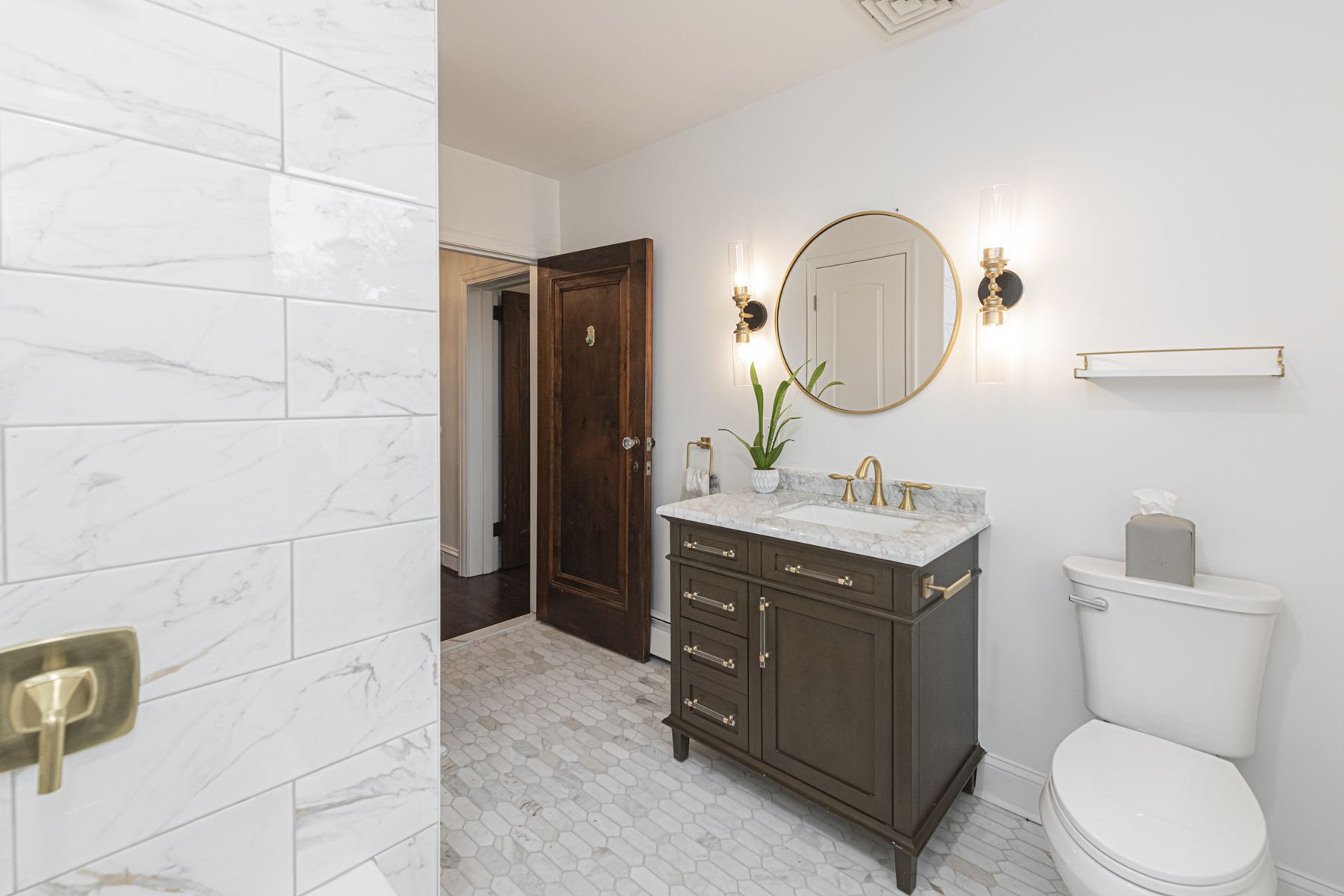 Marble tile, a walnut vanity and a round brass mirror