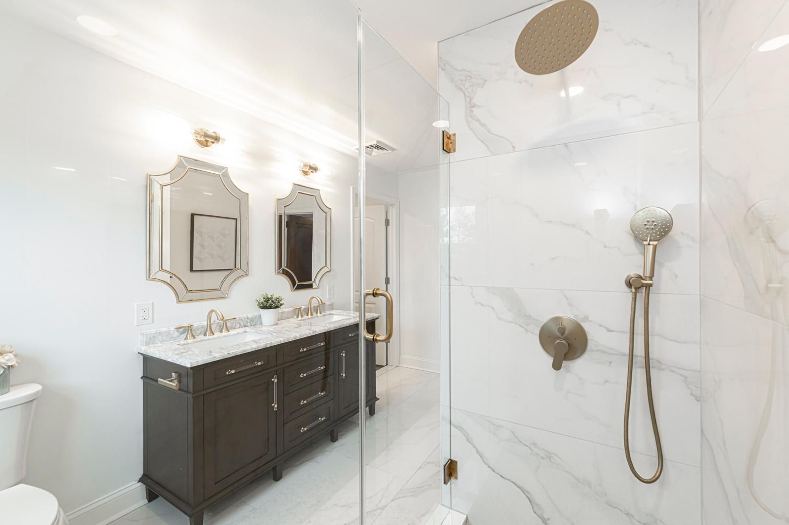 A walnut vanity beside a marble-tiled walk-in shower