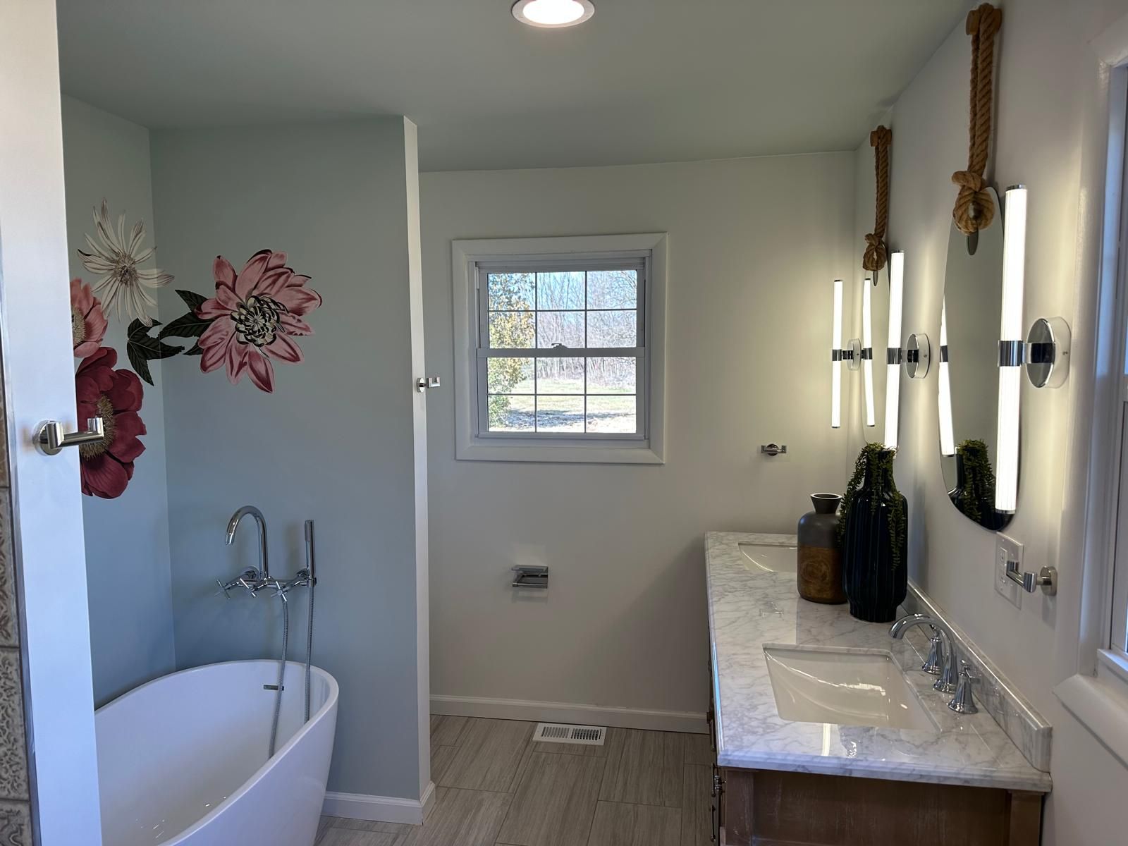 A white vanity with a freestanding tub under the window