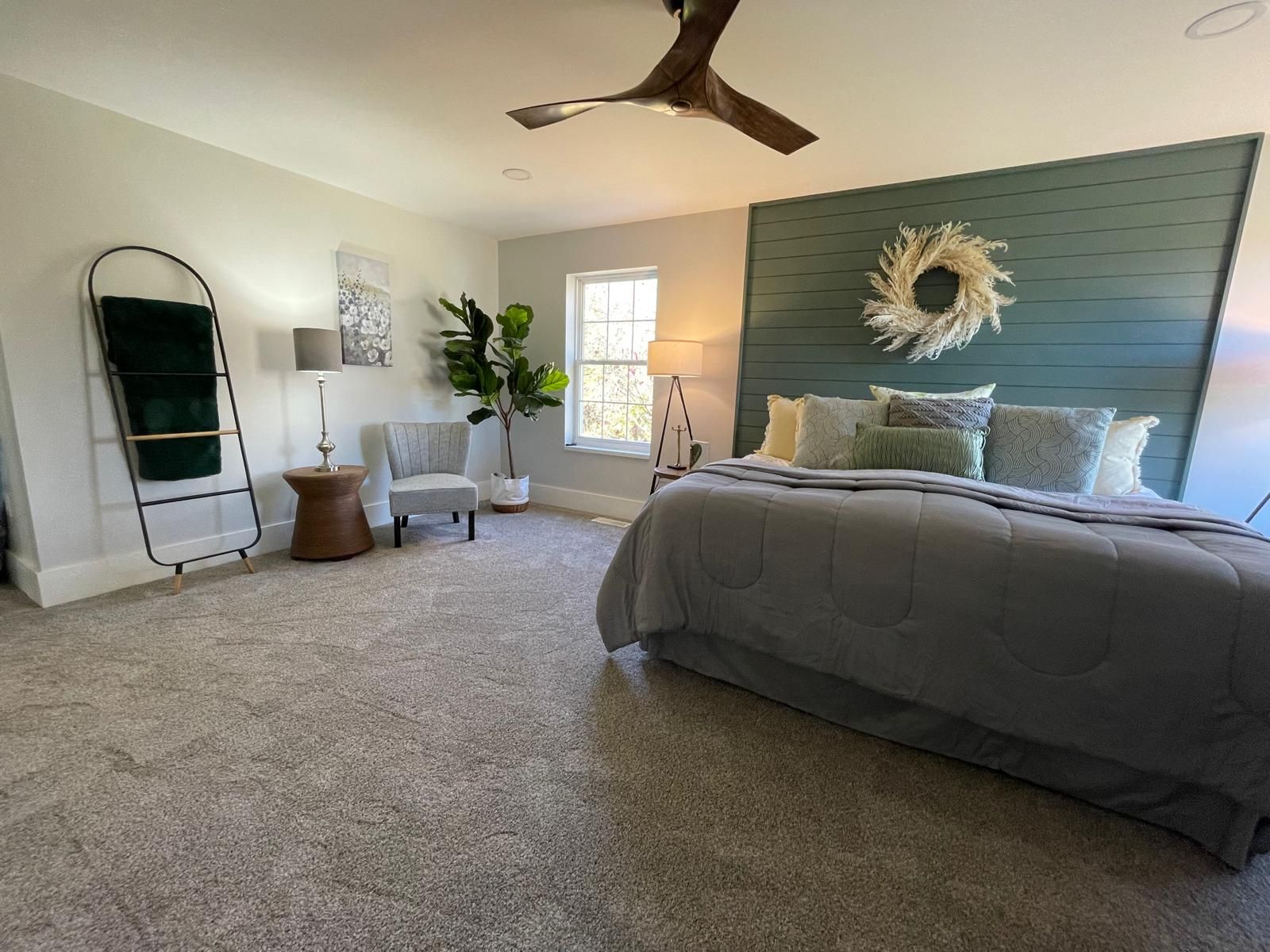 A bedroom with a shiplap wall and a ceiling fan