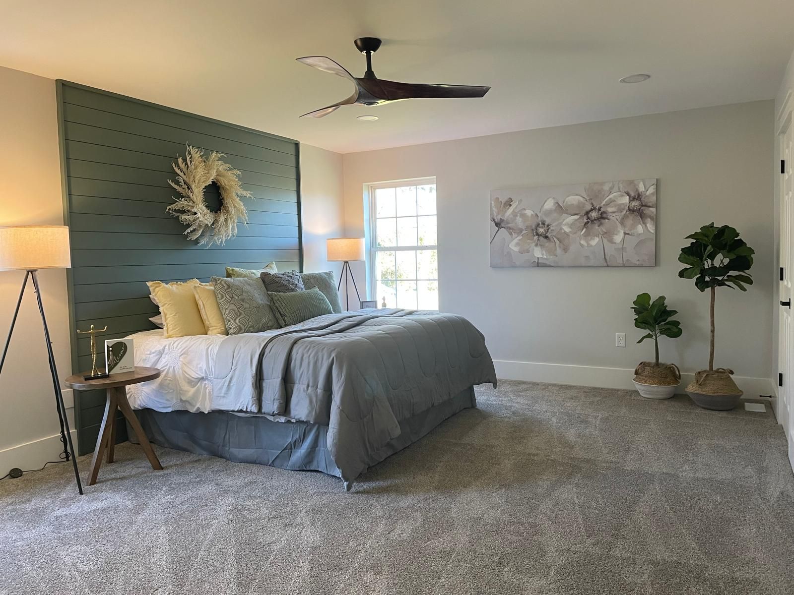 A bedroom with a shiplap accent wall and a ceiling fan