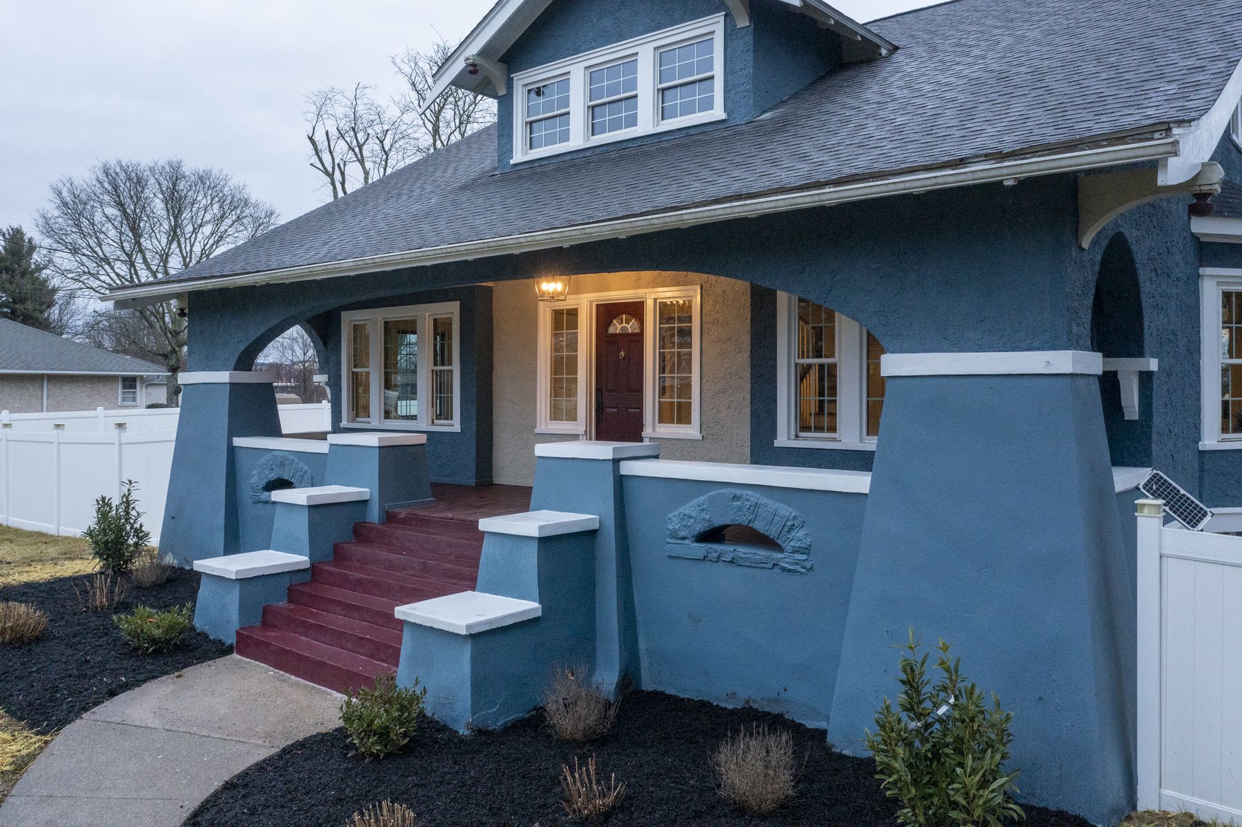 A blue bungalow with a wide front porch and new plantings