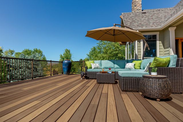 A wood deck with an outdoor sectional and umbrella