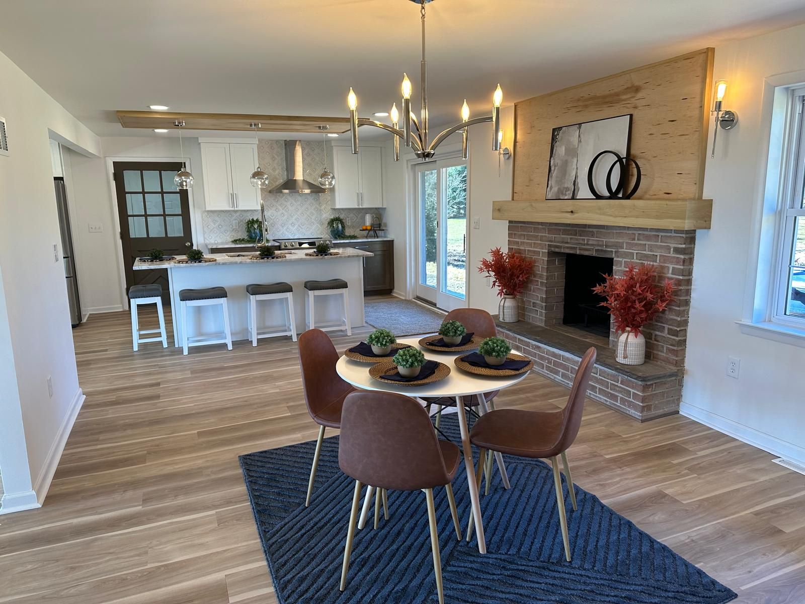 A dining area with a blue rug and a brass pendant