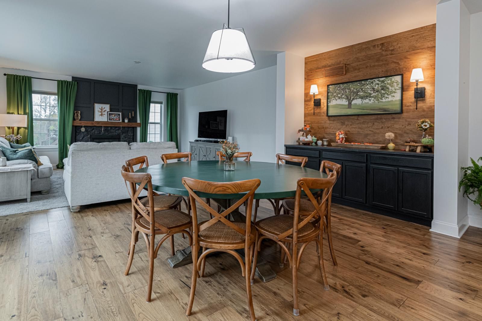A dining table under a pendant, open to the family room