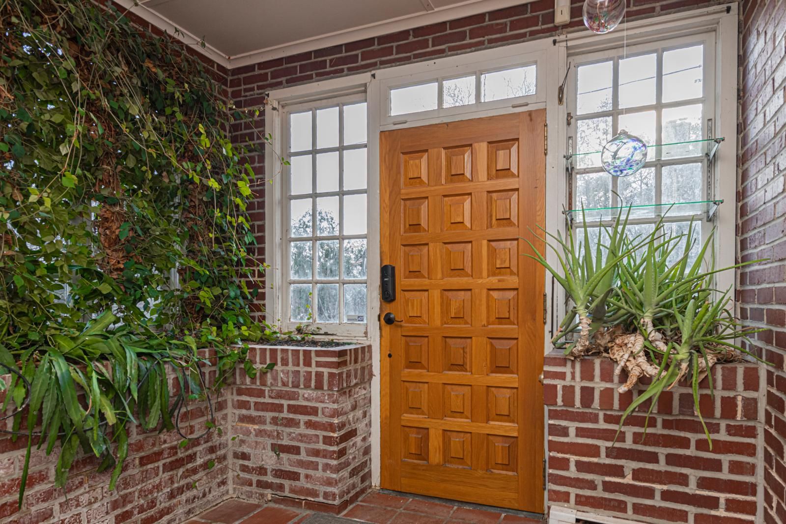 An orange front door in a brick entry