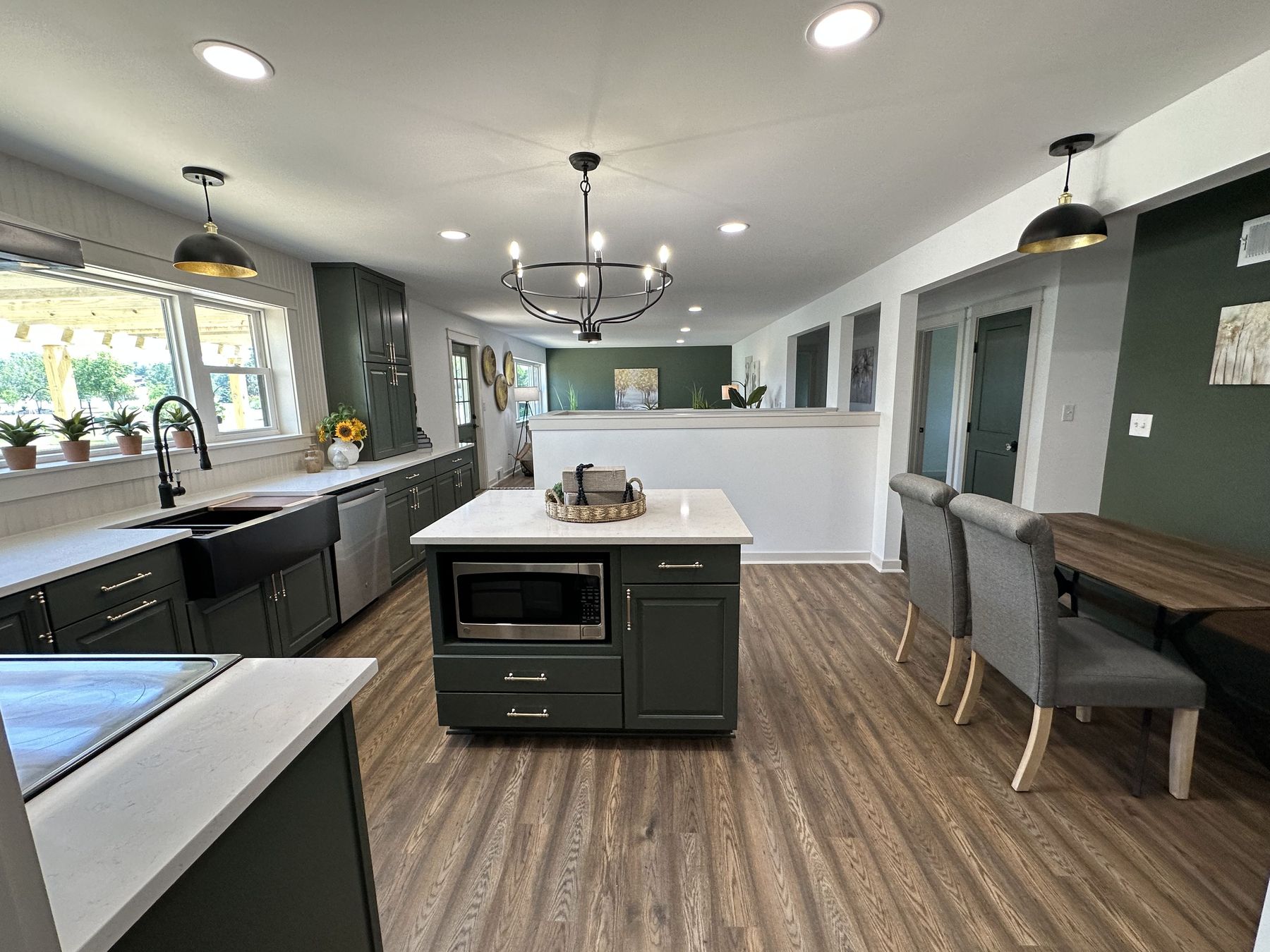 Deep green cabinets, a white quartz island and a chandelier