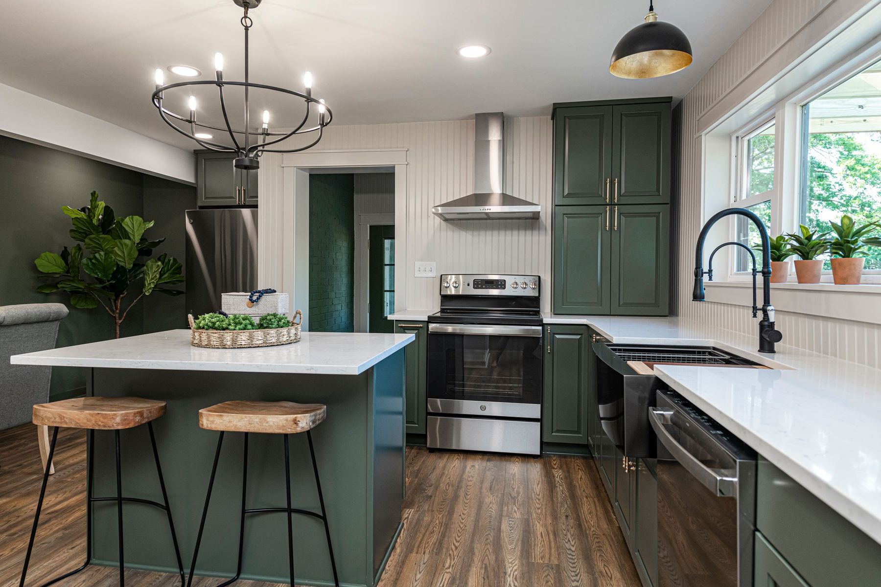 Green cabinets, a stainless hood and a white island with two stools