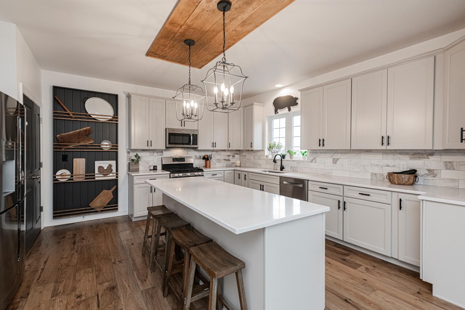 A white kitchen with a long island and a window over the sink